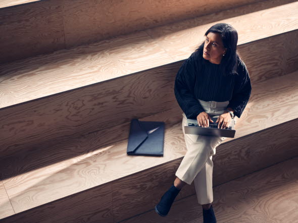 Woman looking in the distance sitting at some stairs with a computer in her lap